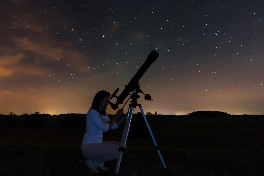 een vrouw die door een telescoop naar de sterren kijkt 